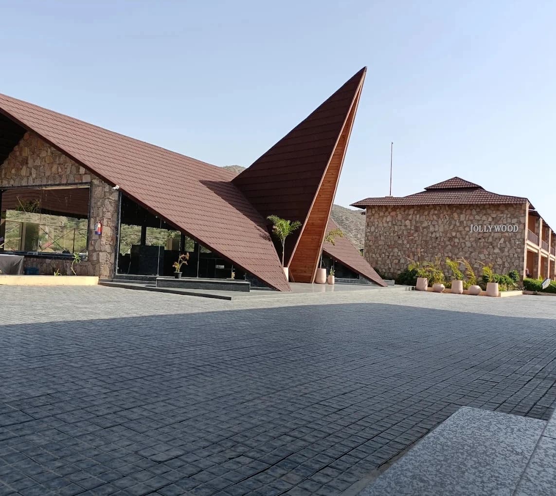 The banquet hall at Jollywood, its peaked red roof rising over a stone facade and an open paved forecourt