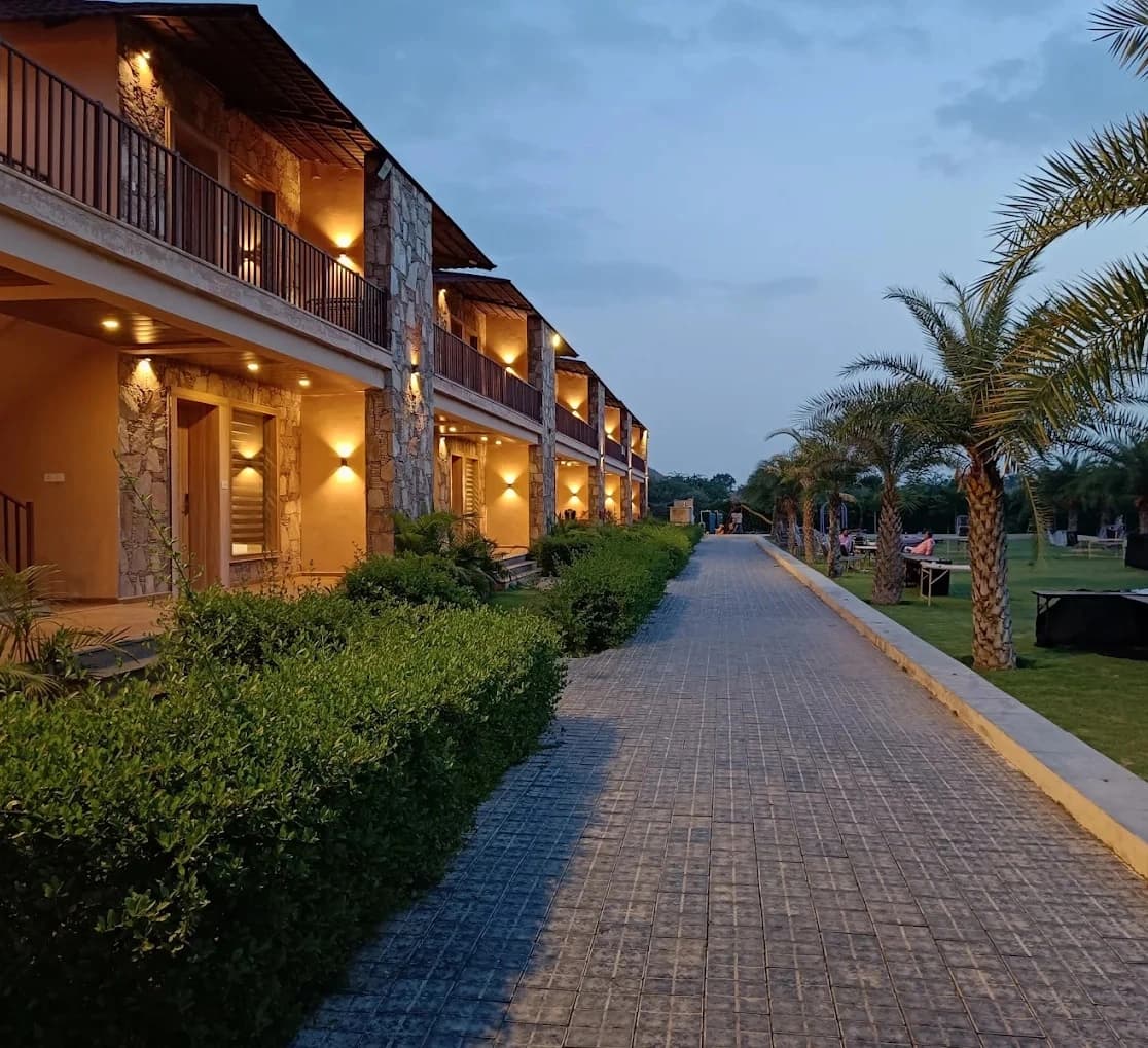 The guest room wing at dusk, lit balconies running along a palm-lined path